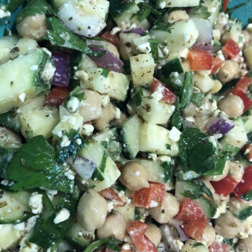 Close up of chickpeas, feta, chopped onions, red pepper and cucumber