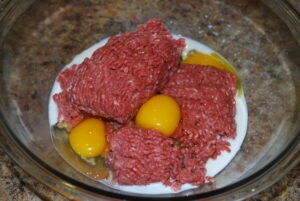 Ground Beef, Eggs, Milk in a glass bowl for prepping meatballs