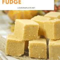 pumpkin spice fudge cute into bite sized pieces and piled on a wooden cutting board.
