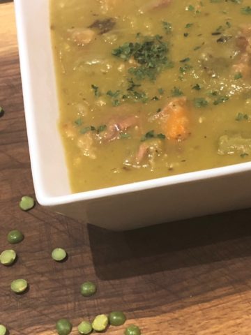 Split Pea & Ham soup in a white bowl on a wooden cutting board