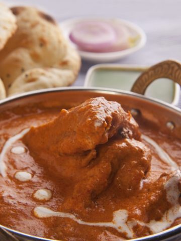 Butter Chicken in a dish with naan in the background