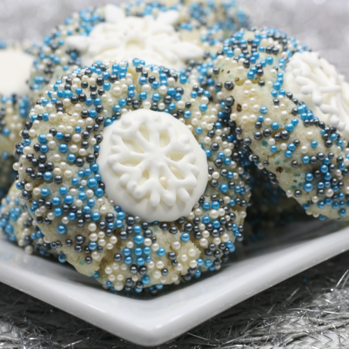 round sugar cookies with winter coloured sparkling sprinkles and an icing snowflake center.