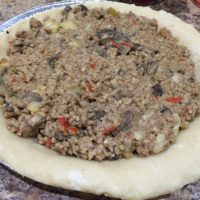 Tourtiere filling inside the bottom of an uncooked pie crust