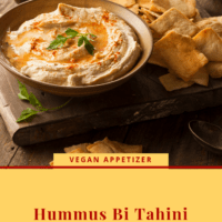 Creamy Hummus drizzle with olive oil and sprinkled with paprika on a wooden board with pita chips