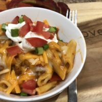 Cooked Penne Pasta, Ground Beef with Salsa Tomato Sauce topped with sour cream, green onions diced tomatoes and cheese
