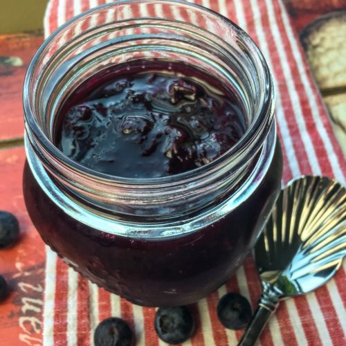 Blueberry Maple compote in a small mason jar, on a red and white linen runner