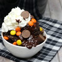 White bowl filled with chocolate peanut butter lava cake, hot fudge, whipped cream andreeses' peanut butter cups