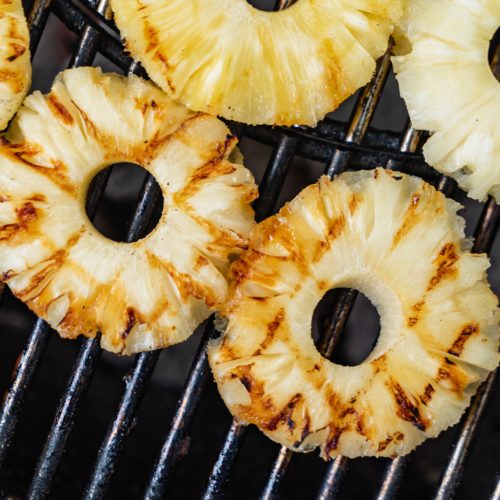 Three pieces of pineapple slices with grill marks on a bbq grill