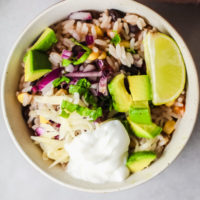Tex Mex Chicken and Rice Burrito Bowl topped with sour cream and red onion.