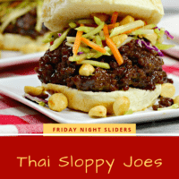 Thai seasoned ground beef on a toasted hamburger bun topped with broccoli slaw, on a white plate with peanuts scattered on it.