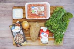 soup ingredients laid out including ground sausage, onion, flour, broth, cream, kale, potato