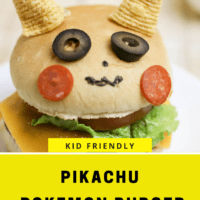 A Cheese burger on a bun decorated to look like Pikachu. 2 bugles are his ears, 2 slices of black olives are his eyes, two thin slices of pepperoni are his cheeks.