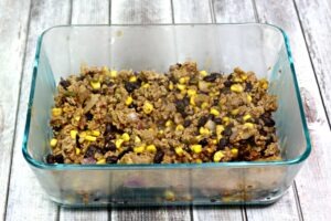 Cooked ground turkey, black beans, corn, red onion in a glass 9X13 dish.