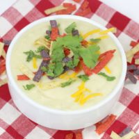 Cauliflower Hatch Green Chile soup in a ceramic white bowl on a red and white checked table cloth