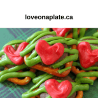 Square pretzels with chocolate pieces, green zig zag candy melt decoration and tiny red hearts