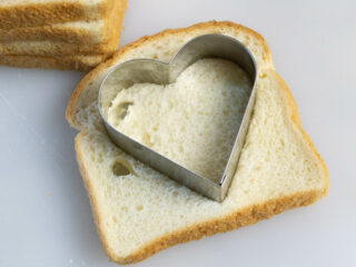 Heart shaped cookie cutter on a piece of white bread. 