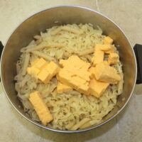 Cubed velveeta cheese in pot with cooked pasta