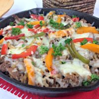 Cast Iron skillet with sliced flank steak, onions and peppers.