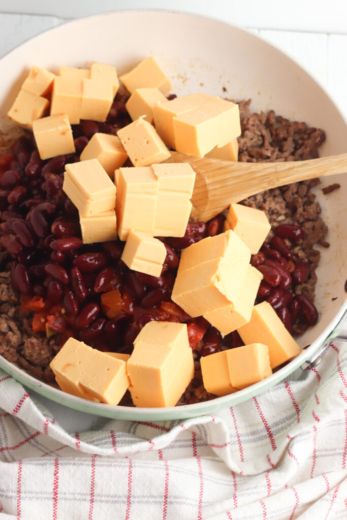 Mixing velveeta cubes into beef and bean mixture
