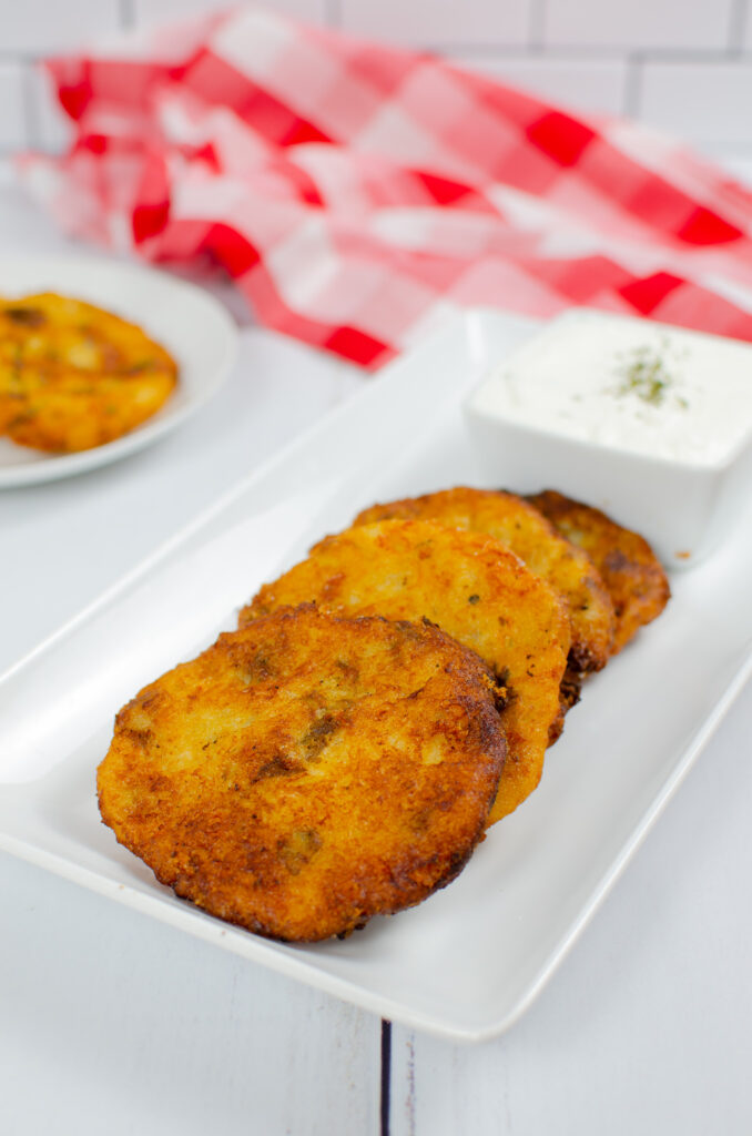 Golden fried mashed potato patties on a white serving platter. 